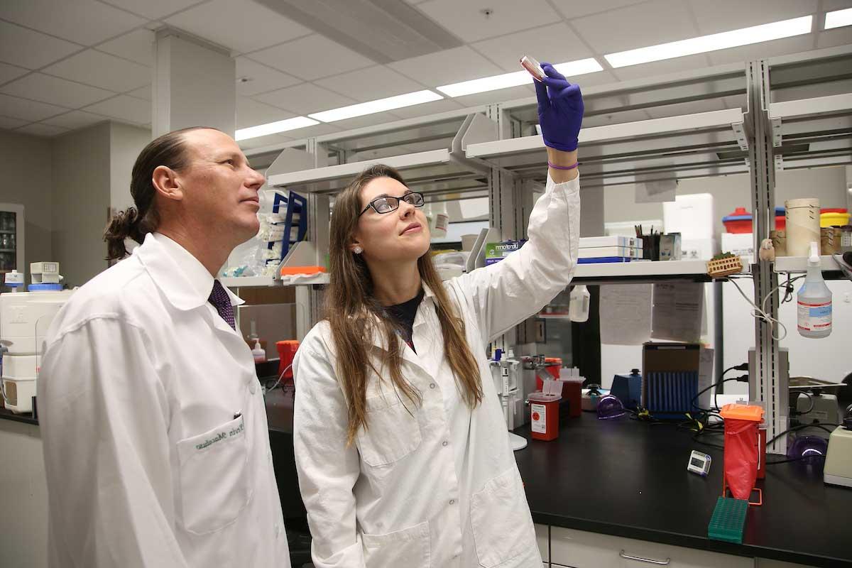 研究生研究员汉娜·劳凯提斯和凯文·马卡卢索博士.D., 微生物学和免疫学教授兼主席, 在这张资料照片中，他在传染病实验室工作.